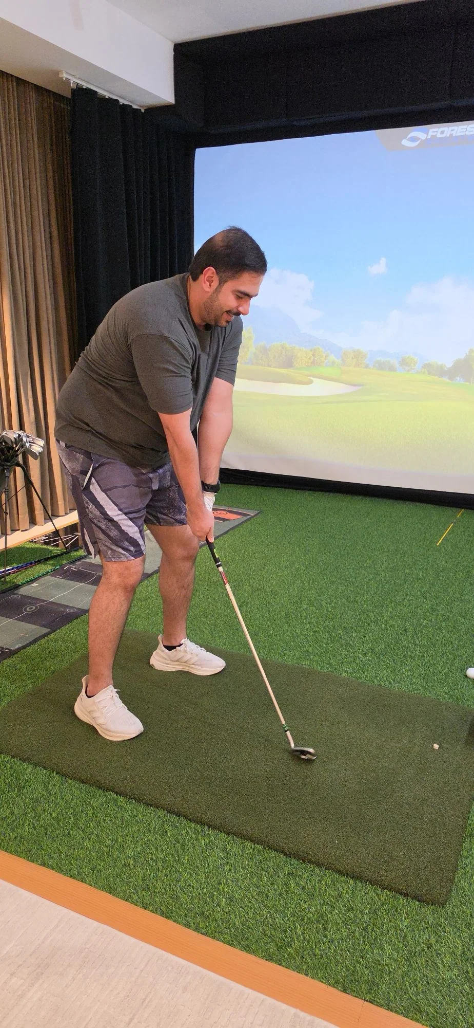 Golfer at address on the hitting mat during an indoor ASUBURE fitting session